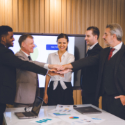 People during an M&A deal shaking hands and smiling because they have learned ho0w to navigate Indemnity Deductibles and Caps successfully.
