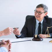 An M&A lawyer working with clients and finalizing a deal, smiling because he was able to ensure it was a smooth process.