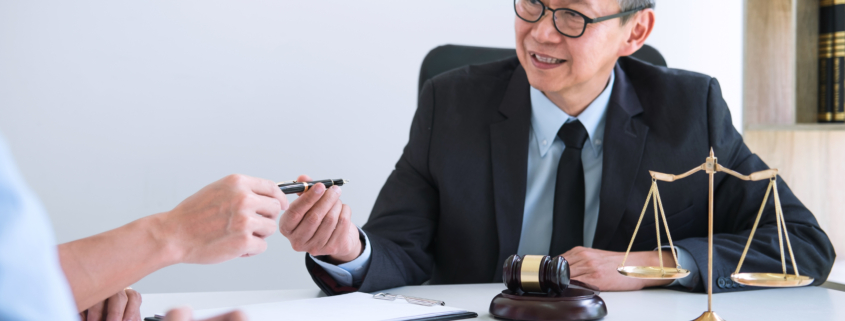 An M&A lawyer working with clients and finalizing a deal, smiling because he was able to ensure it was a smooth process.
